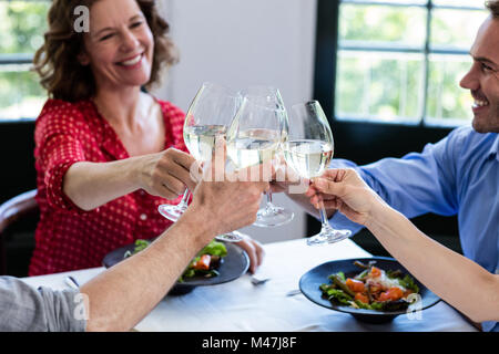 Happy friends toasting wine glass tout en déjeunant Banque D'Images