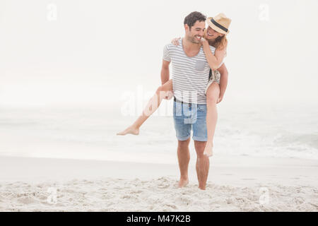Man giving a piggy retour à la femme sur la plage Banque D'Images