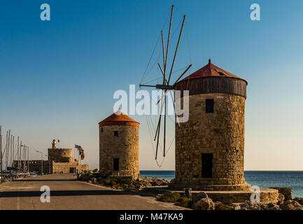 Situé sur la longue vague disjoncteur sur le port de Mandraki, Rhodes, Grèce, stand ces moulins à vent médiévale, un rappel du passé. Banque D'Images