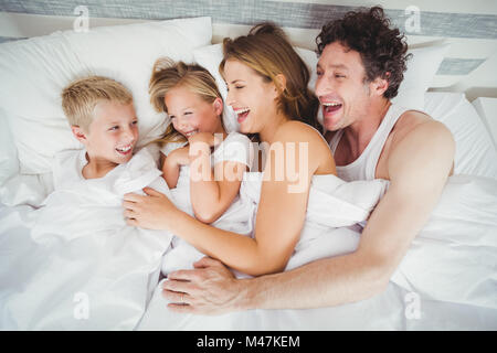 High angle view of smiling family enjoying on bed Banque D'Images