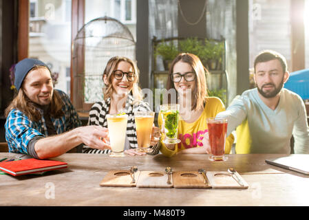 Les amis clinking glasses dans le café moderne Banque D'Images