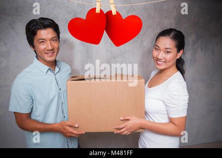 Image composite de l'heureux couple tenant une boîte en carton déménagement Banque D'Images