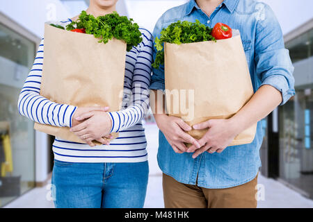 Image composite de mid section of couple holding grocery bags Banque D'Images