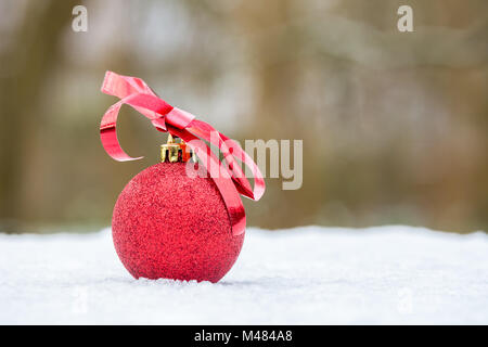 Boule de Noël rouge avec arc en plein air dans la neige Banque D'Images