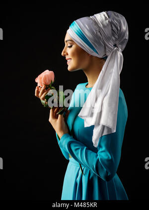 Femme musulmane en robe bleue avec rose sur noir Banque D'Images