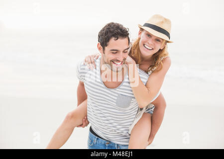 Man giving a piggy retour à la femme sur la plage Banque D'Images