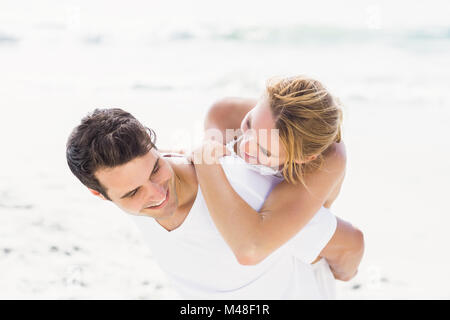 Man giving a piggy retour à la femme sur la plage Banque D'Images