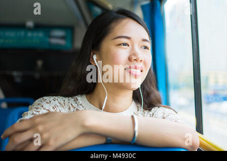 Fille d'écouter de la musique sur un trajet en bus public Banque D'Images