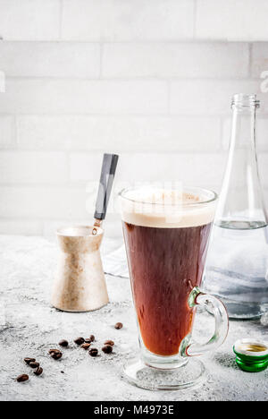 Verre moderne très tendance. Café espresso avec de l'eau minérale, avec cafetière et haricots rôtis, fond noir en gris, copy space Banque D'Images