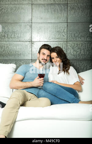 Beautiful couple buvant un verre de vin sur le canapé Banque D'Images