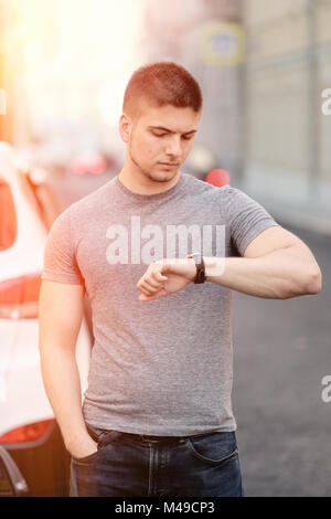 Jeune homme ooking sur sa montre-bracelet Banque D'Images