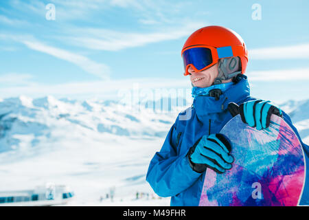 Image de l'homme sportif casque en regardant ailleurs avec snowboard sur fond de snowy hill Banque D'Images