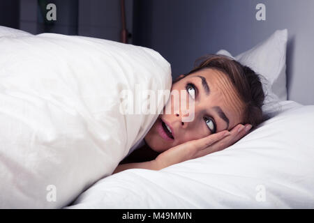 Peur Woman Pulling drap de lit sur le lit la nuit Banque D'Images