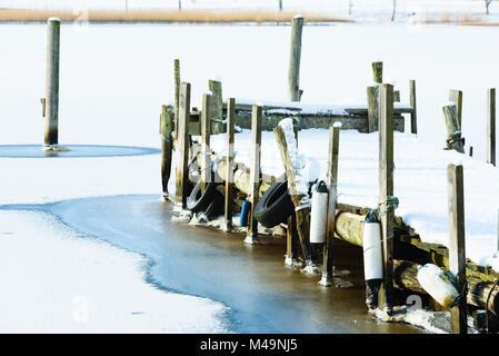 Ancienne jetée en bois dans la glace et la neige. Les poteaux d'amarrage le long de la côte et en mer. Rive opposée visible à travers la baie. Banque D'Images