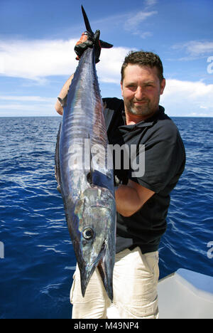 La pêche en haute mer, pêche au gros. prise de poissons. Lucky fisherman holding un énorme poisson wahoo Banque D'Images