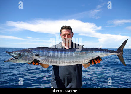 La pêche en haute mer, pêche au gros. prise de poissons. Lucky fisherman holding un énorme poisson wahoo Banque D'Images