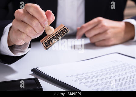 Close-up de personne à l'aide de mains stamper sur le document avec le texte approuvé Banque D'Images