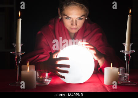 Belle jeune diseuse tenir la main autour d'une boule rougeoyante Banque D'Images