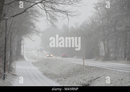 Le trafic de faible densité se déplaçant lentement, sur une route au cours d'importantes chutes de neige qui cause une réduction de la visibilité. Banque D'Images