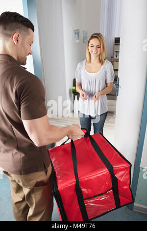Delivery Man Giving un grand sac rouge à Happy Young Woman Banque D'Images