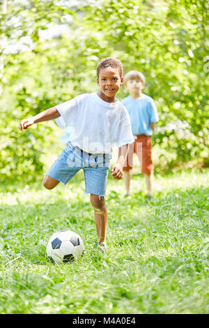 African boy joue au football avec un ami dans le parc en été Banque D'Images