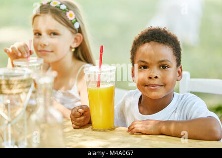 African boy c'est boire du jus d'orange dans la maternelle internationale Banque D'Images