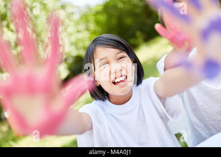 Asian girl s'amuse tout en peignant avec de la peinture de doigt en maternelle Banque D'Images