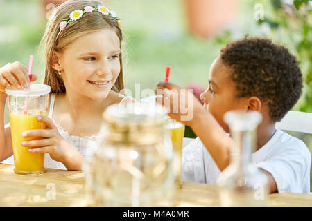 Deux enfants ayant le petit déjeuner dans le jardin d'enfants de boire du jus d'orange Banque D'Images