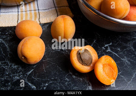 Organique mûres les abricots dans une passoire en acier. Composition dans un style rustique - jaune bio abricots juteux dans son ensemble et passoire en acier et des moitiés d'abricots o Banque D'Images