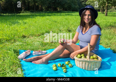 Femme assise sur couverture avec les poires au verger Banque D'Images