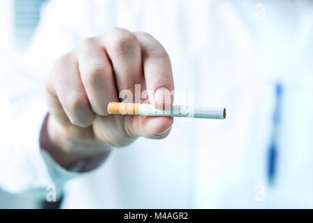 Doctor holding une cigarette entre les doigts. Cesser de fumer concept. Banque D'Images