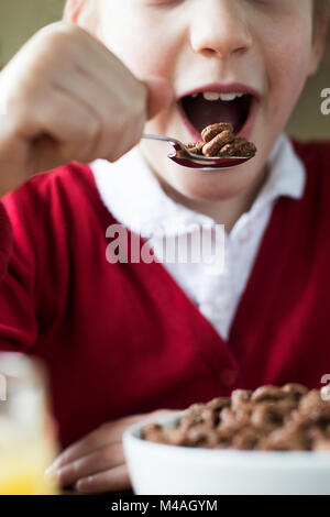 Close Up of Girl Wearing School Uniform mangeant bol de céréales pour petit déjeuner sucrées dans la cuisine Banque D'Images