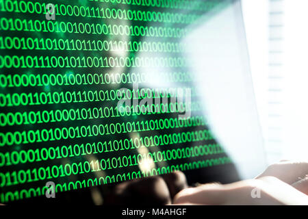 Hacker code écrit avec un ordinateur portable. De nombres binaires 0 et 1 sur l'écran du moniteur. Menace de sécurité cybernétique, l'attaque et le crime en ligne concept. Banque D'Images