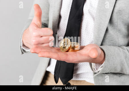 Close up of man holding pile de bitcoins sur sa paume d'or sur fond gris isolé Banque D'Images