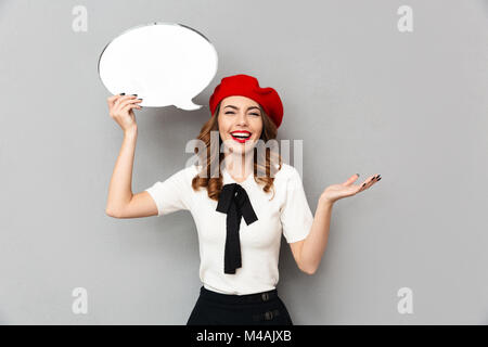 Portrait of a smiling schoolgirl habillés en tenue uniforme bulle vide et isolé de rire sur fond de mur gris Banque D'Images