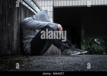 La dépression, l'isolement social, la solitude, la santé mentale et la discrimination concept. Triste, seule, déprimé et malheureux. Personne assise à capuchon. Banque D'Images