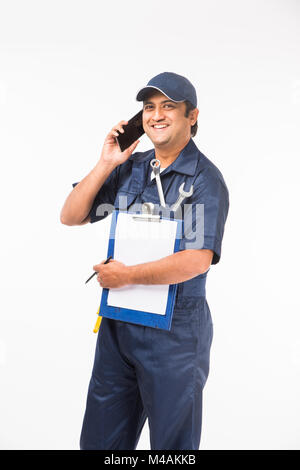 Heureux indiens auto mechanic en costume bleu et la tenue de l'outil clé dans l'action, isolé sur fond blanc Banque D'Images