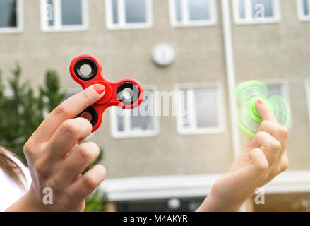 Teenage girl Playing with deux fidget tourniquets à la récréation ou que le cour de l'école. Banque D'Images