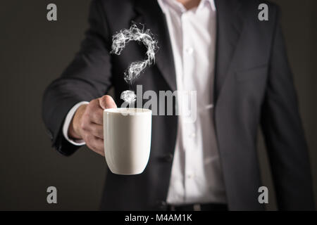 Point d'interrogation à partir de la bouilloire vapeur. Fumée secondaire formant un symbole. L'homme d'affaires en costume tenant une boisson chaude dans un mug et tasse de thé. Banque D'Images