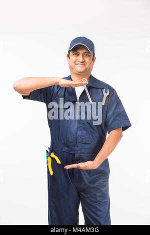 Heureux indiens auto mechanic en costume bleu et la tenue de l'outil clé dans l'action, isolé sur fond blanc Banque D'Images