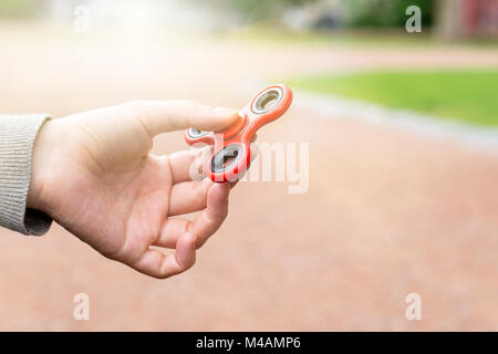 Femme ou fille holding red fidget spinner dans la main sur une journée ensoleillée dans un parc à l'extérieur. Banque D'Images