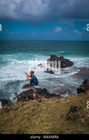 L'homme sur la falaise à prendre des photos de la mer des vagues à Gris-Gris sur la côte sud de l'île Maurice Banque D'Images