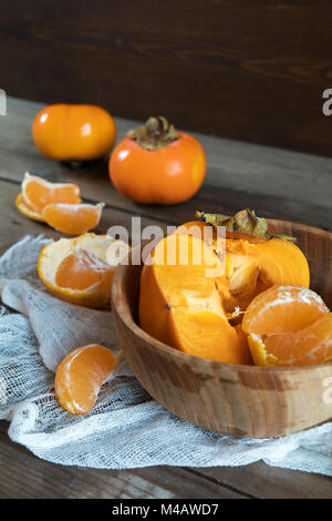 Le kaki et les tangerines fraîches fruits dans bol Banque D'Images