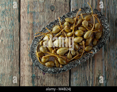 Caper marinés de baies dans un plat en métal . Fruits comestibles de Capparis . Les baies sont utilisées comme garniture.old wooden background. Vue d'en haut. Banque D'Images