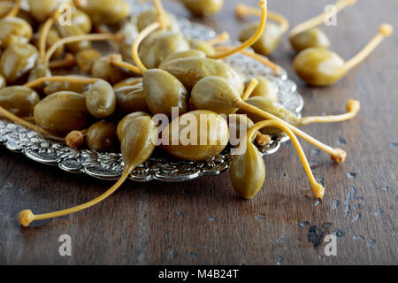 Caper marinés de baies dans un plat en métal . Fruits comestibles de Capparis . Les baies sont utilisées comme garniture.old wooden background. Banque D'Images