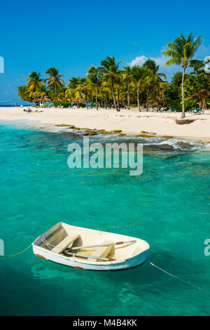 Petit bateau dans les eaux turquoises avant qu'une plage de sable fin sur Palm Island, îles Grenadines,St. Vincent et les Grenadines,Caraïbes Banque D'Images