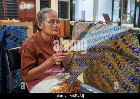 Femme indonésienne applique de la cire fondue sur le batik avec un canting (outil jouté). Batik Winotosastro shop, Yogyakarta, Java, Indonésie. Banque D'Images