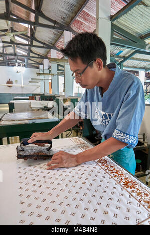 Batik Maker imprime de la cire chaude sur un chiffon avec un tampon de cuivre. Batik Winotosastro shop, Yogyakarta, Java, Indonésie. Banque D'Images