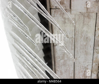 La neige fondue et grand de glaçons pendant le toit de la maison. Focus sélectif. Banque D'Images