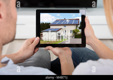 Close-up of Couple Looking At Maison avec des panneaux solaires sur At Digital Tablet Banque D'Images
